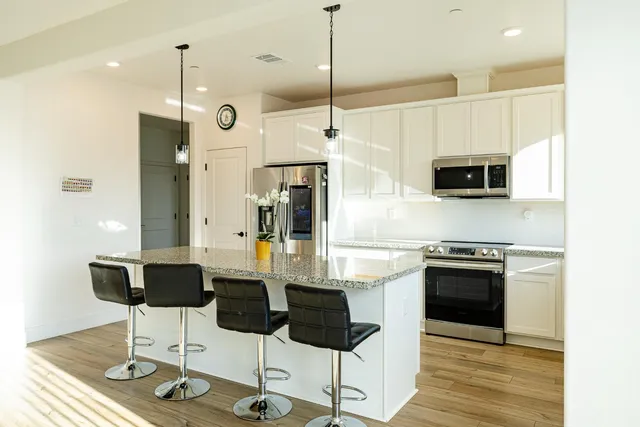 a kitchen with stainless steel appliances kitchen island granite countertop a stove a refrigerator and a wooden floor