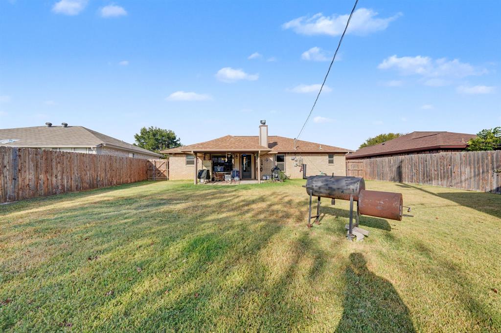 7624 Maple Hill Road Watauga, TX 76148 - Photo 20 of 20 Expansive backyard featuring a large grass area, wood privacy fencing, and a covered patio with a concrete slab