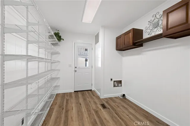 a view of a hallway with wooden floor and cabinet