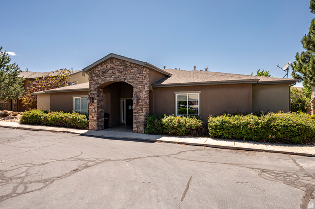 1177 Northfield Road, Unit 26 Cedar City, UT 84721 - Photo 35 of 45 Stucco exterior building featuring a stone veneer arched entrance, mature shrubbery, and a paved lot