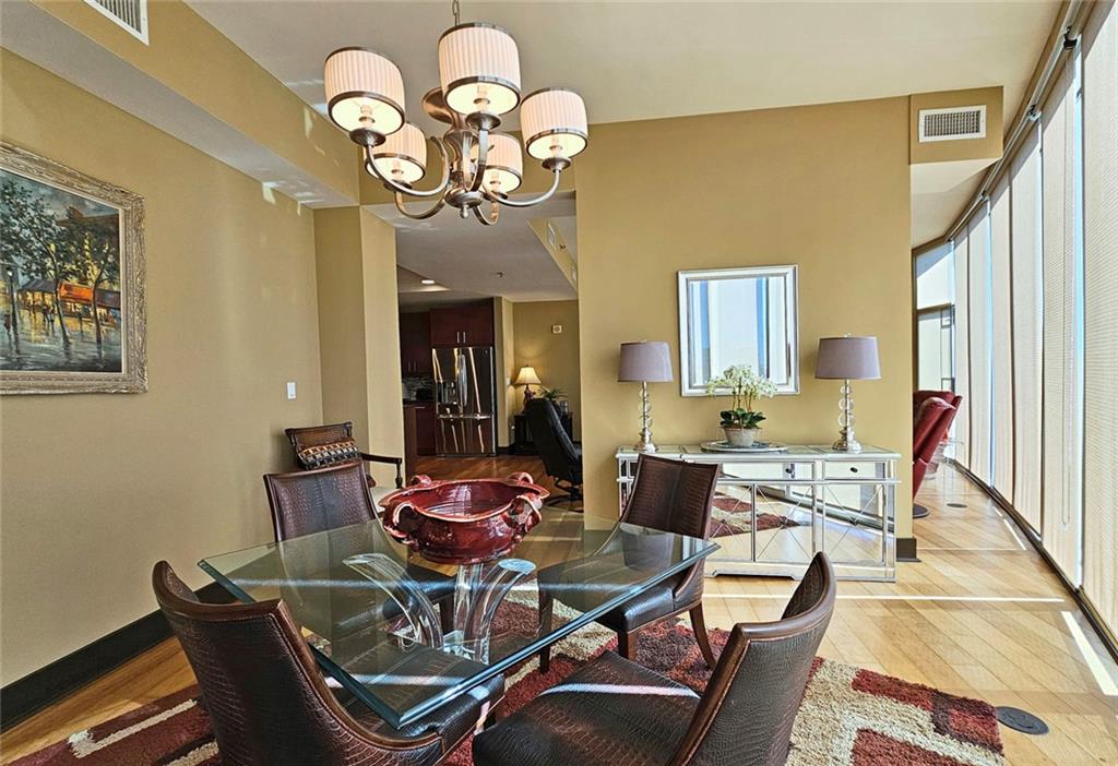 4561 Olde Perimeter Way, Unit 1202 Atlanta, GA 30346 - Photo 12 of 46 a dining room with wooden floor a chandelier a wooden table and chairs