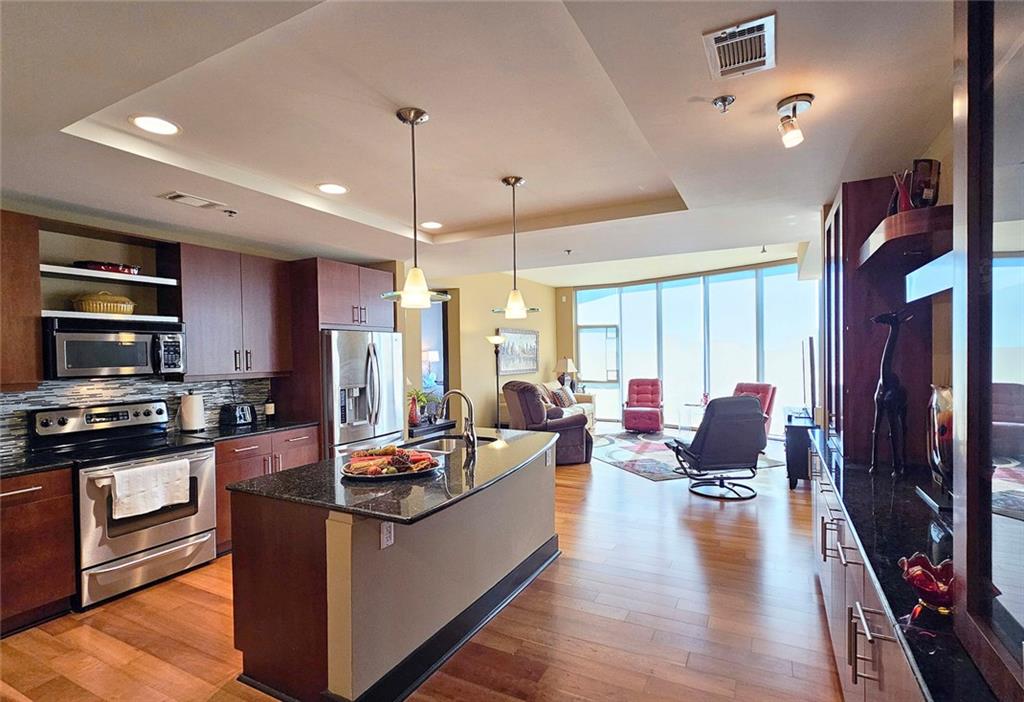 4561 Olde Perimeter Way, Unit 1202 Atlanta, GA 30346 - Photo 5 of 46 a living room with stainless steel appliances kitchen island granite countertop a stove and a refrigerator