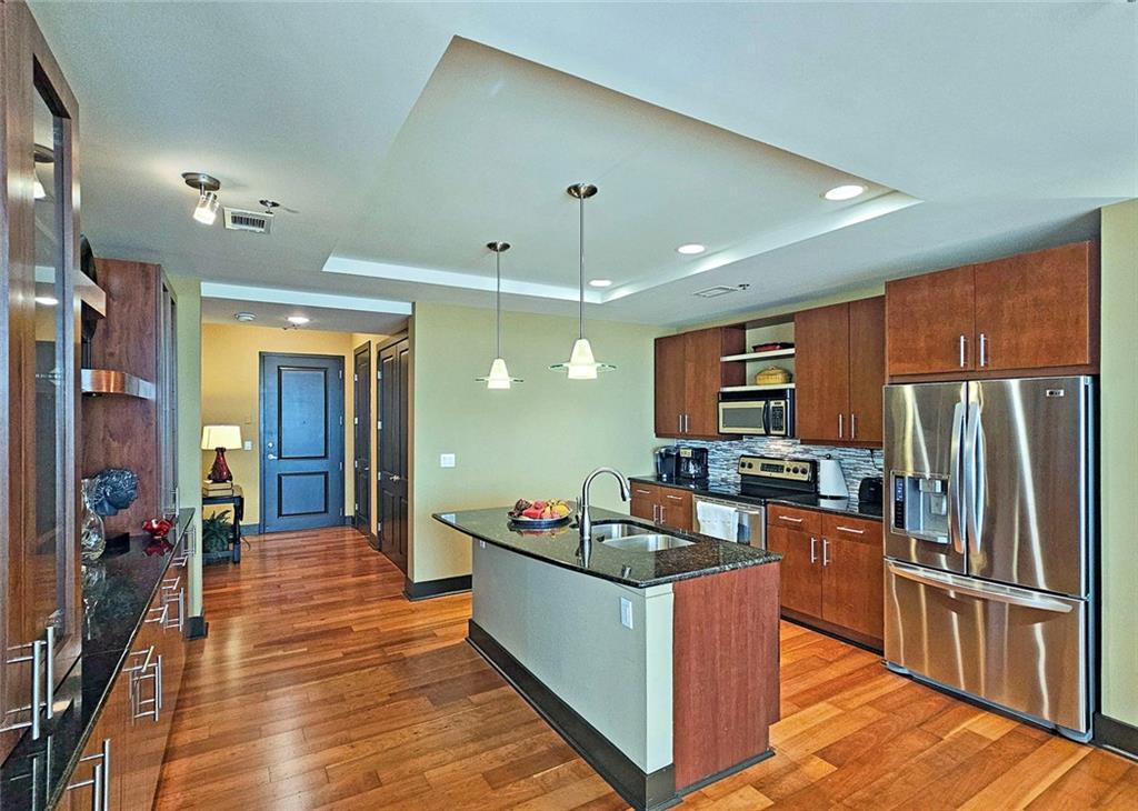 4561 Olde Perimeter Way, Unit 1202 Atlanta, GA 30346 - Photo 6 of 46 a large kitchen with stainless steel appliances granite countertop a stove refrigerator and a kitchen island