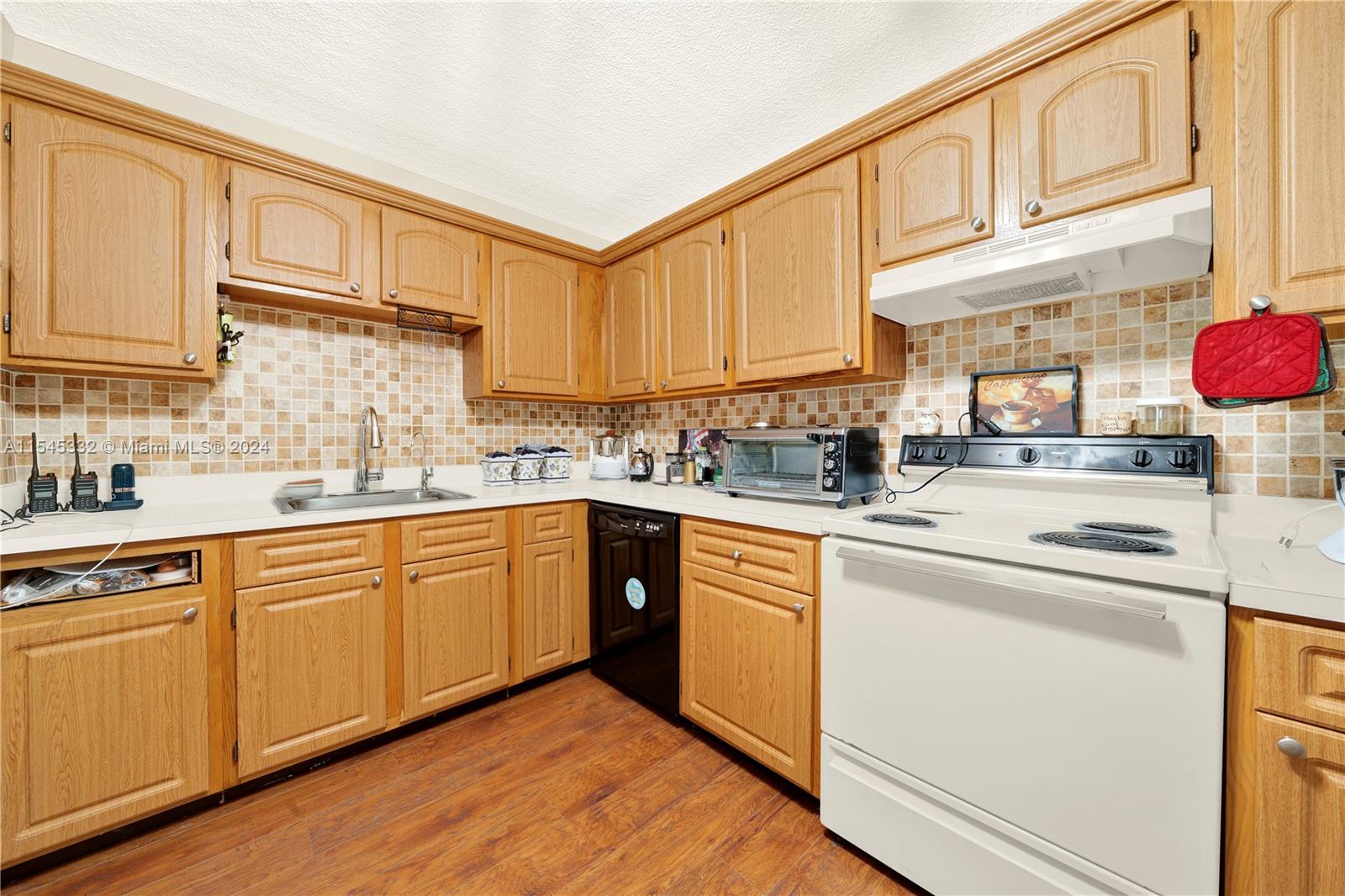 a kitchen with stainless steel appliances granite countertop a sink dishwasher stove and white cabinets with wooden floor
