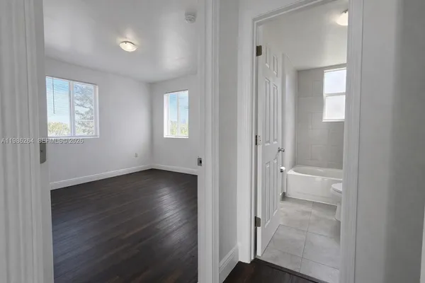 an empty room with wooden floor and a bathroom