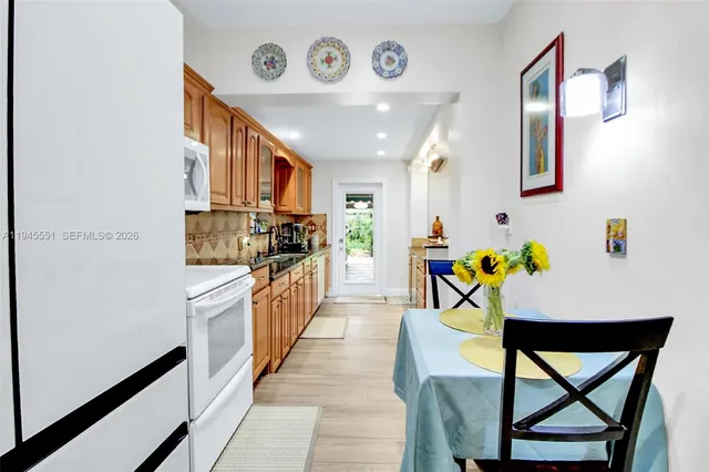 a kitchen with stainless steel appliances granite countertop a dining table chairs and a refrigerator