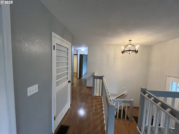 a view of a hallway with wooden floor and stairs