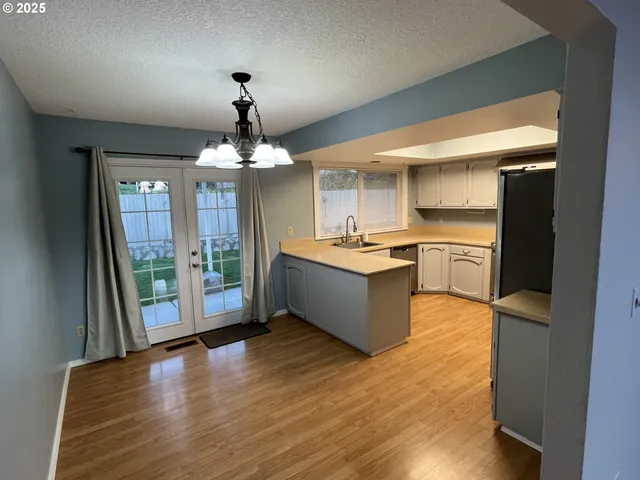 a large kitchen with stainless steel appliances granite countertop a refrigerator a sink dishwasher a stove and white countertops with wooden floor