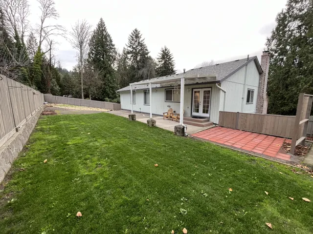 a view of a backyard with table and chairs wooden fence
