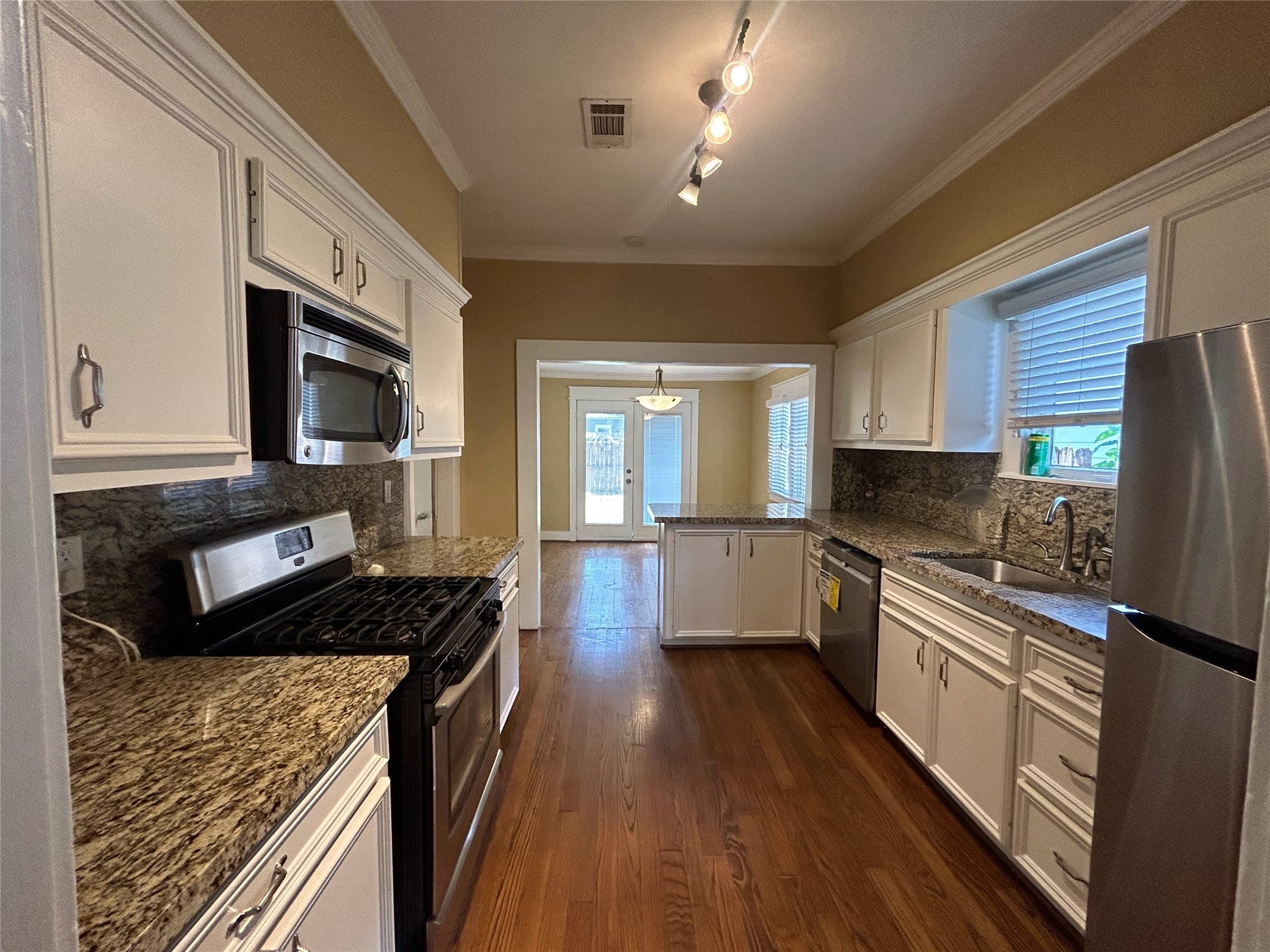 209 Walton Street Houston, TX 77009 - Photo 9 of 24 a kitchen with granite countertop a stove top oven a sink dishwasher a refrigerator and white cabinets with wooden floor