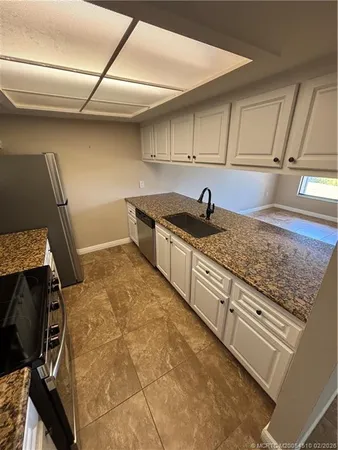 a kitchen with granite countertop a sink a stove and cabinets