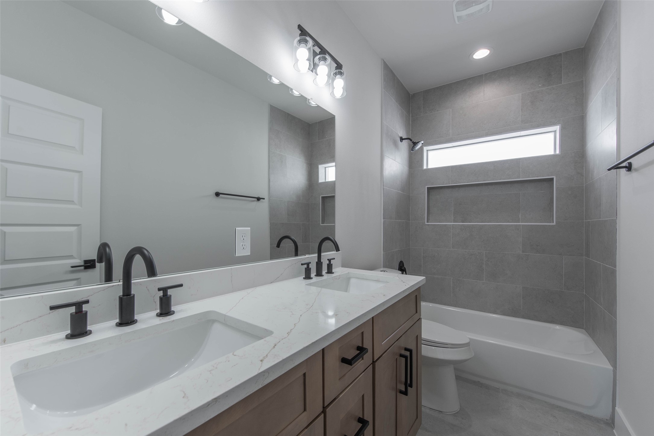 9311 Jutland Road Houston, TX 77033 - Photo 21 of 28 The secondary bath features dual vanities, ample storage, and a tub-shower combo, offering both comfort and functionality.