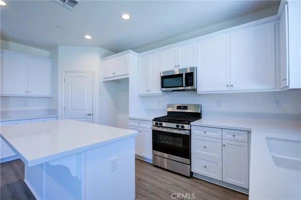 a kitchen with granite countertop a sink dishwasher a stove and a refrigerator with wooden floor