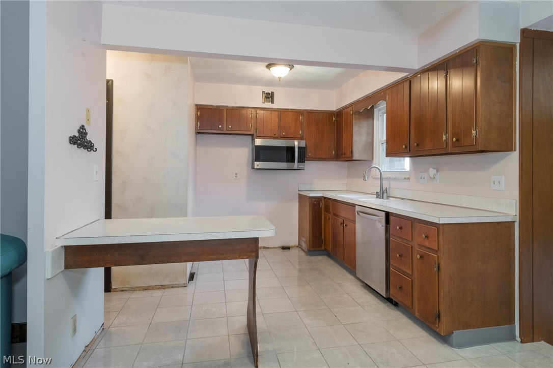 6484 State Road Parma, OH 44134 - Photo 11 of 36 Functional kitchen featuring wood cabinetry, Formica countertops, and a breakfast bar.