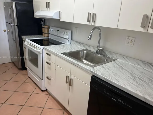 a kitchen with granite countertop a sink a stove and cabinets