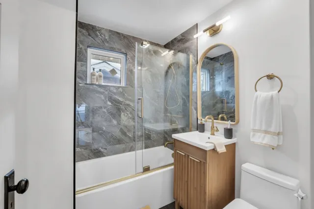 a bathroom with a bathtub shower sink mirror and toilet