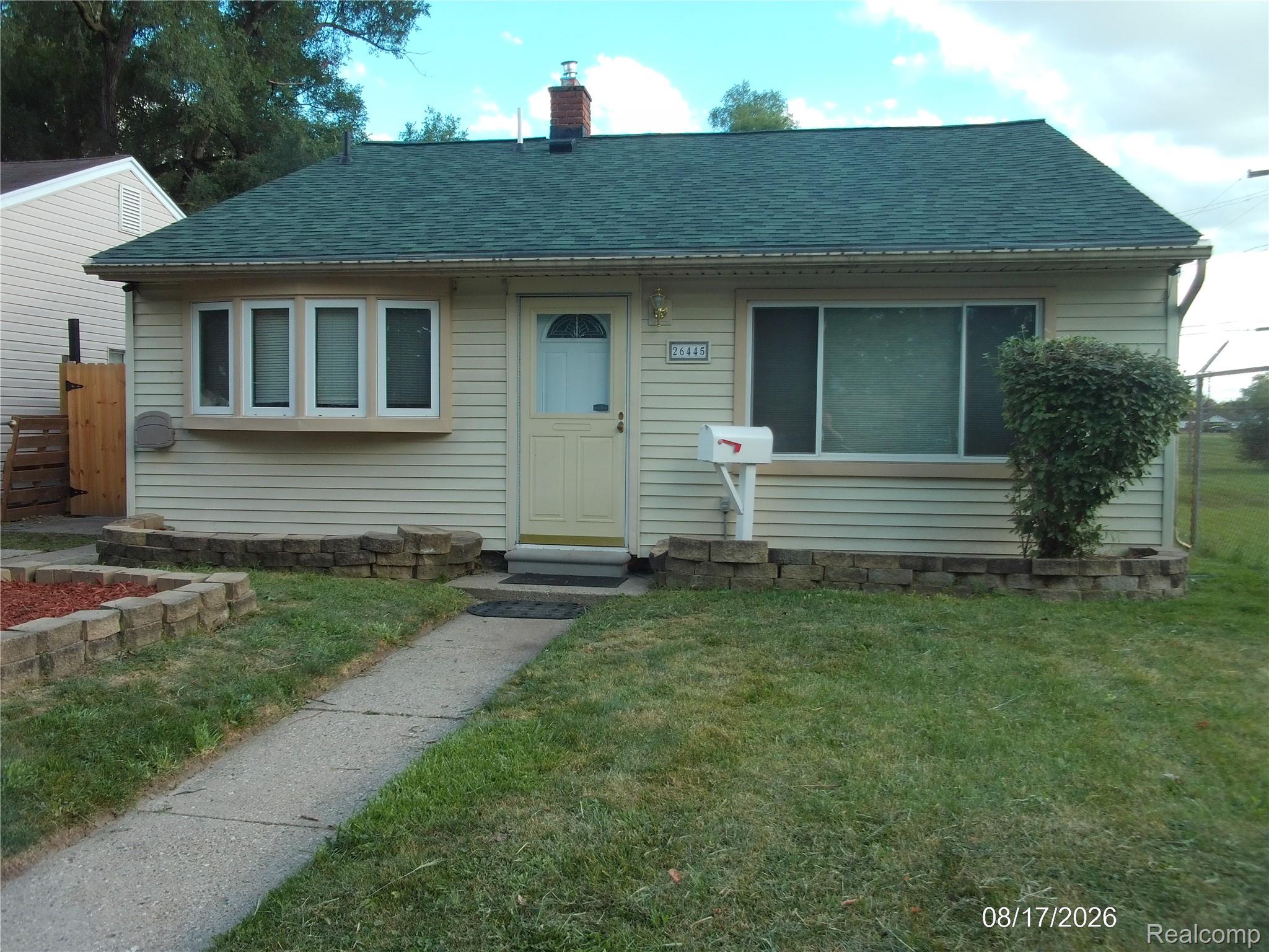 Light-colored siding exterior with a green shingle roof