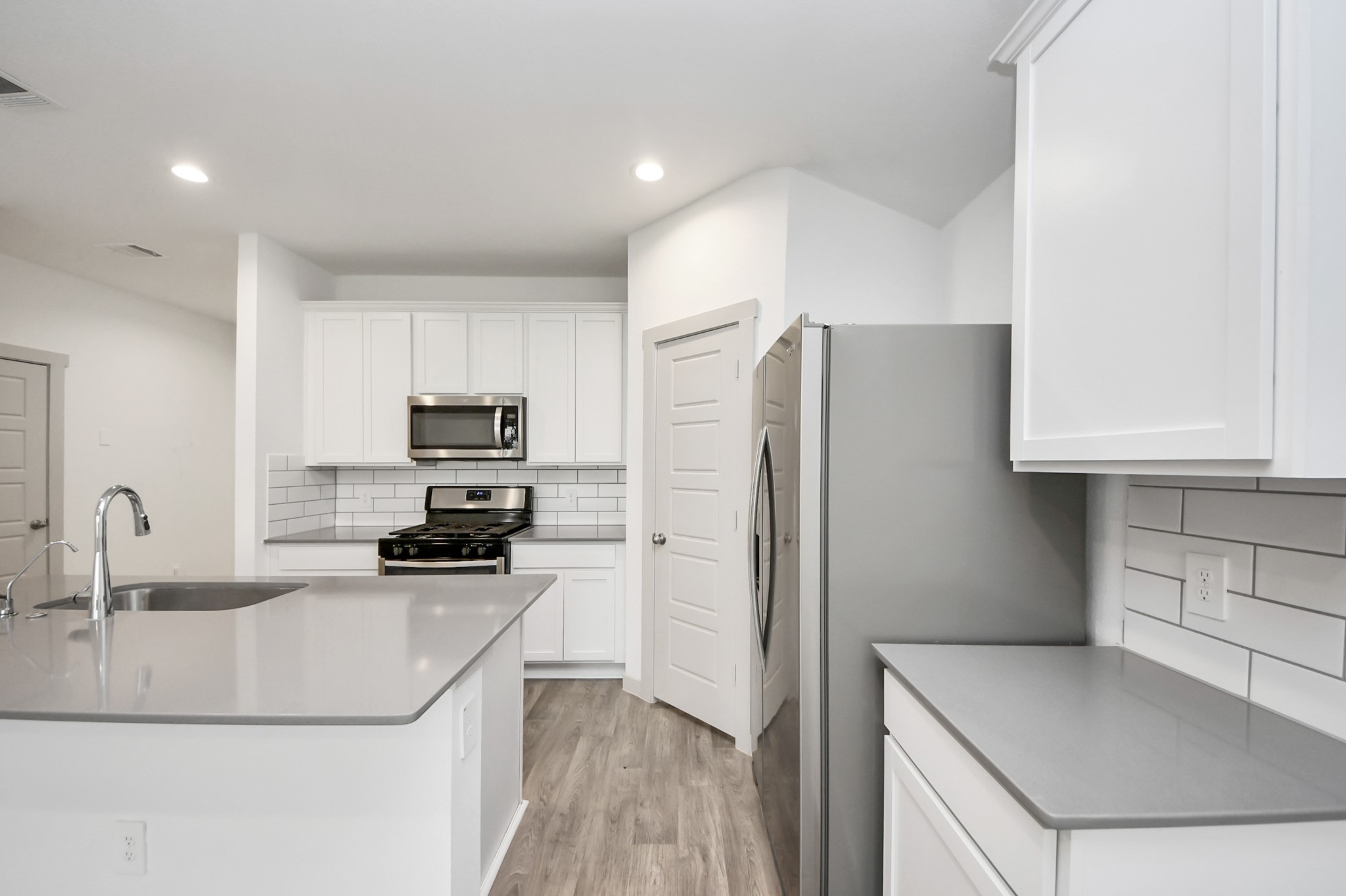 7806 Cattleman Vly Drive Rosharon, TX 77583 - Photo 13 of 40 a kitchen with a refrigerator sink and white cabinets