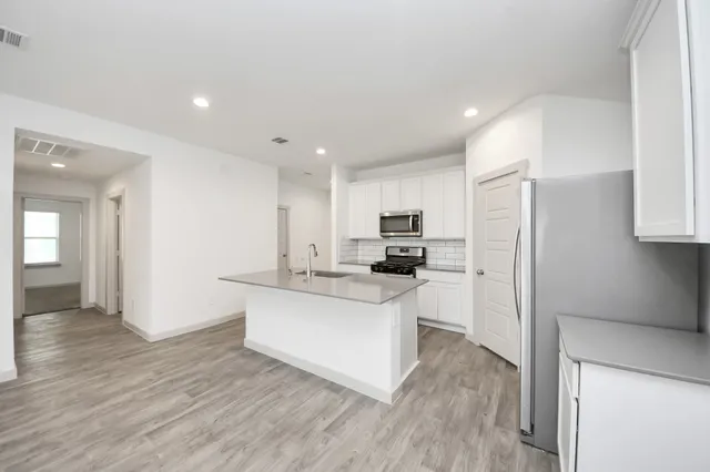 a kitchen with stainless steel appliances a refrigerator and a stove top oven