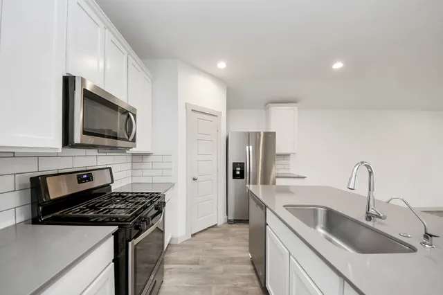 a kitchen with stainless steel appliances granite countertop a sink stove and refrigerator