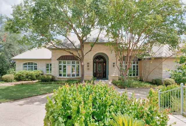 a front view of a house with a yard and potted plants