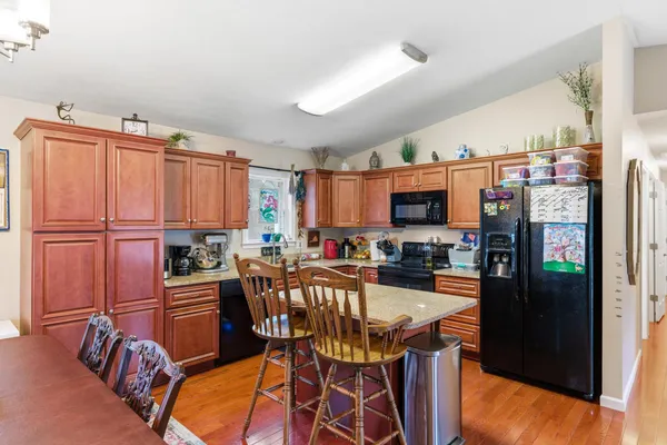 a kitchen with stainless steel appliances granite countertop a refrigerator a stove a sink dishwasher and a dining table with wooden floor