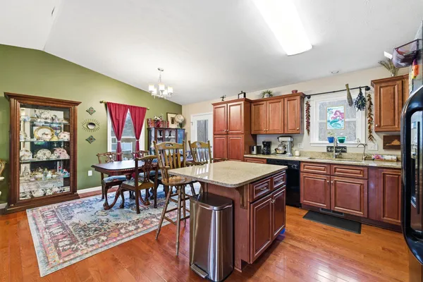 a kitchen with stainless steel appliances granite countertop a stove top oven a dining table and chairs with wooden floor