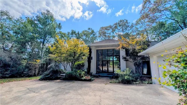 a view of a house with potted plants and large trees