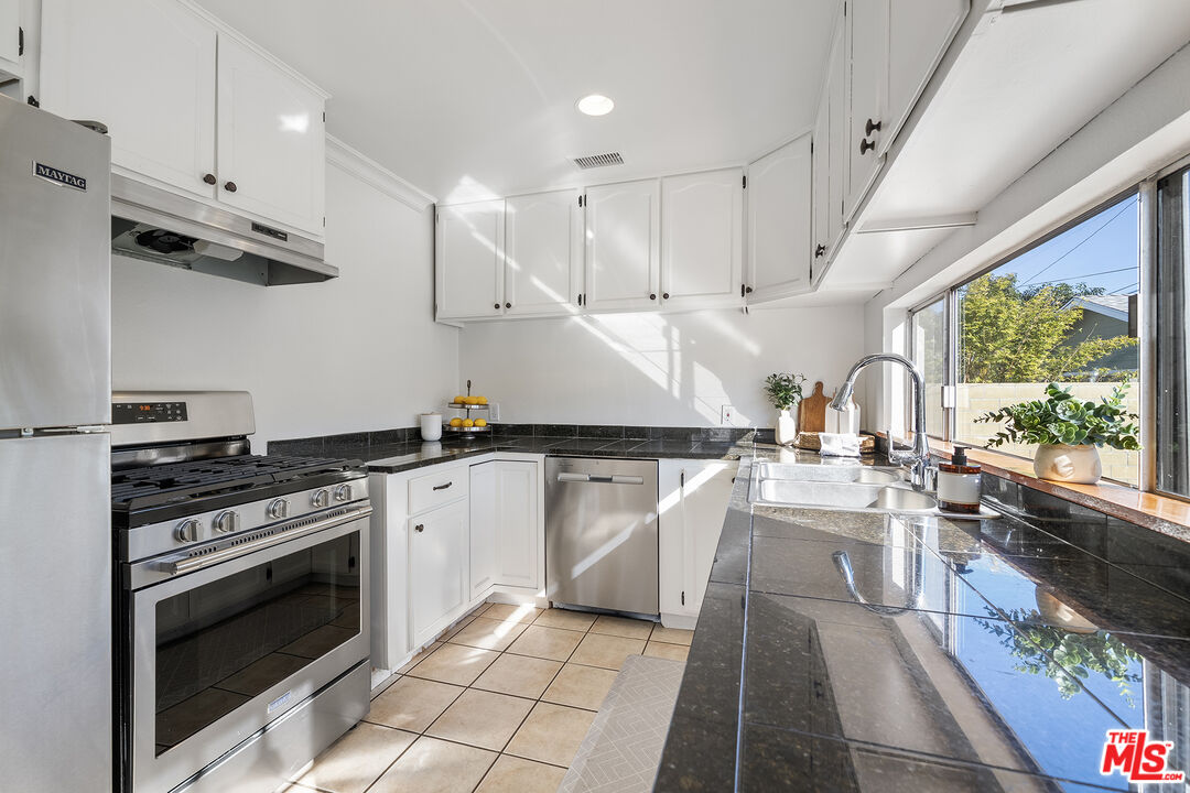 4516 Walnut Avenue Long Beach, CA 90807 - Photo 12 of 35 a kitchen with stainless steel appliances granite countertop a stove a sink dishwasher and a oven with white cabinets