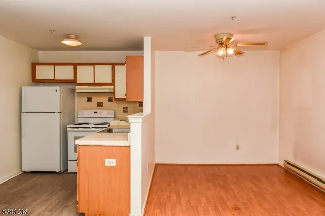 a view of kitchen and empty room with wooden floor