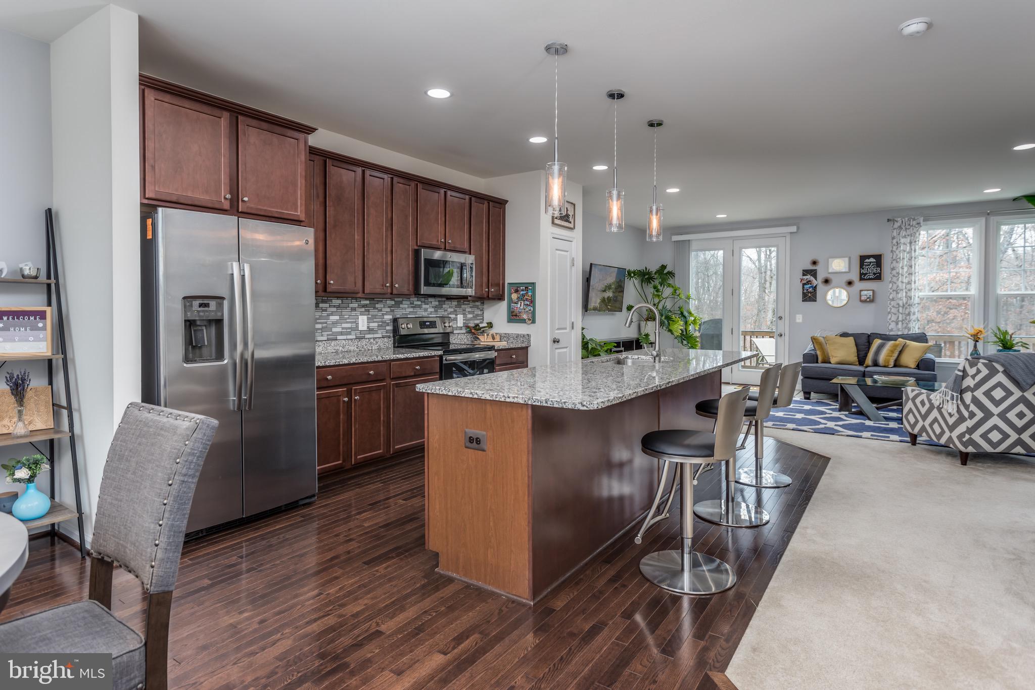 148 Solara Drive Winchester, VA 22602 - Photo 11 of 32 a kitchen with stainless steel appliances granite countertop a refrigerator a stove a sink a dining table and chairs with wooden floor