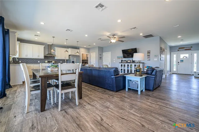 a living room with stainless steel appliances kitchen island granite countertop wooden floor a dining table and chairs