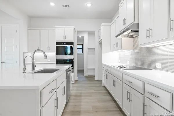 a kitchen with granite countertop white cabinets and stainless steel appliances
