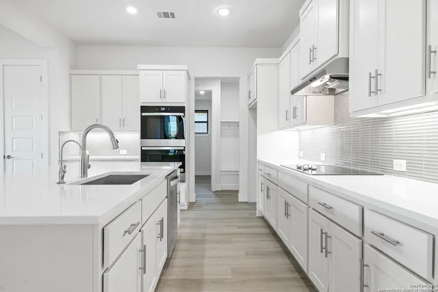 a kitchen with granite countertop white cabinets and stainless steel appliances