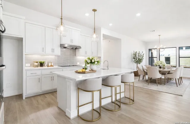 a kitchen with stainless steel appliances granite countertop a stove a sink a dining table and chairs with wooden floor