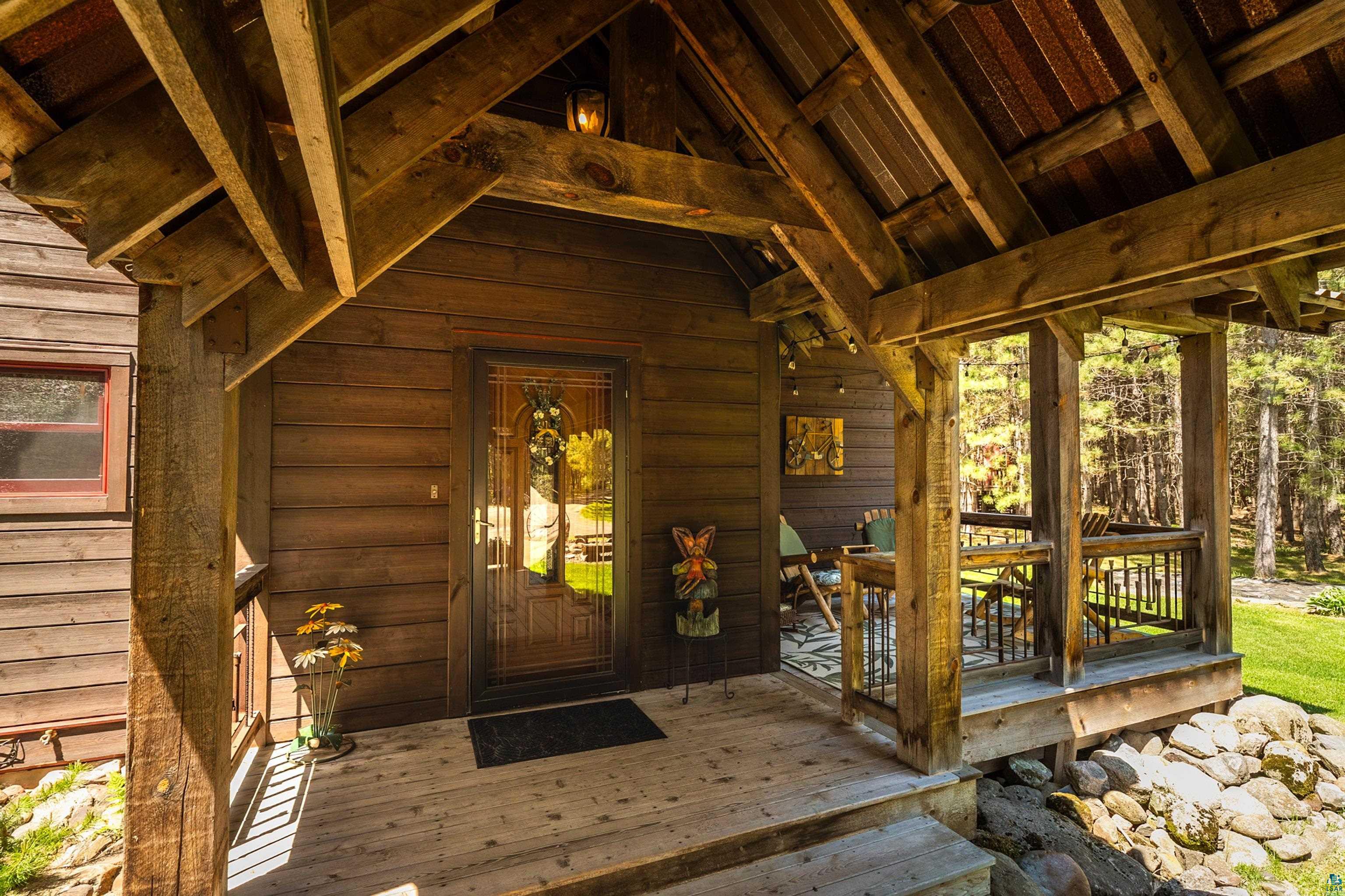 75 East Stark Road Esko, MN 55733 - Photo 5 of 87 Wood-clad exterior with a covered porch featuring exposed timber framing and a paneled entry door with decorative glass