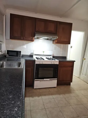 a kitchen with granite countertop a stove top oven microwave and cabinets