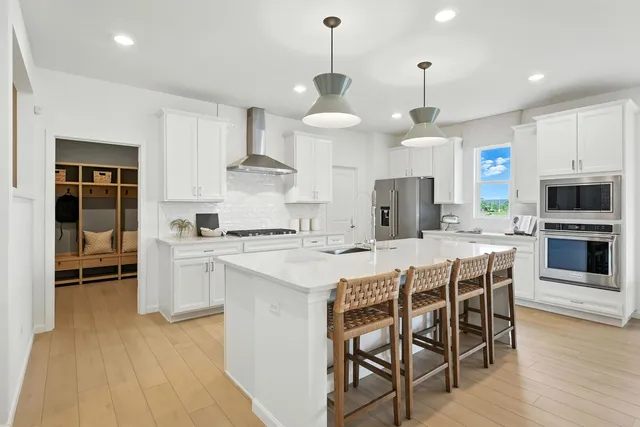 a kitchen with stainless steel appliances kitchen island granite countertop a table chairs and a refrigerator