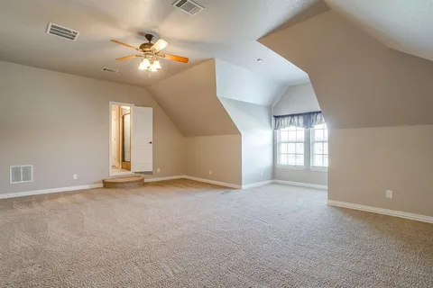 an empty room with windows and chandelier fan
