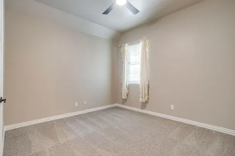an empty room with a window and a ceiling fan