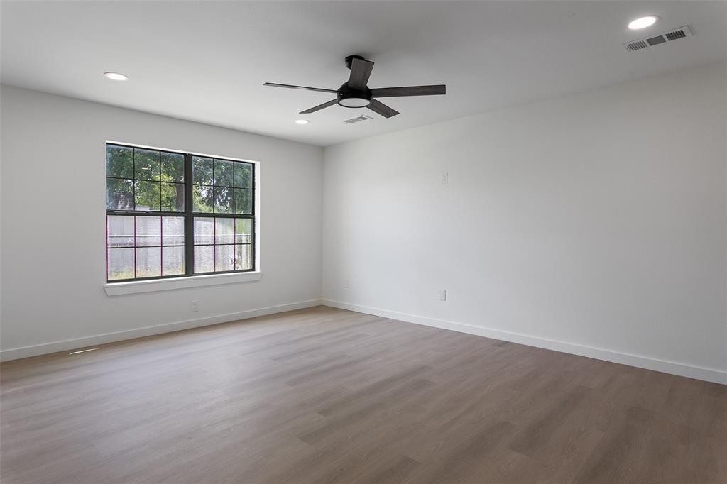 1346 South Reno Road Springtown, TX 76082 - Photo 16 of 24 Spacious room featuring wood-finish flooring, a large window with black grilles, and a ceiling fan with integrated lighting