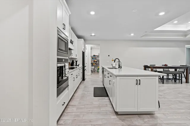a kitchen with stainless steel appliances a table chairs refrigerator and wooden cabinets