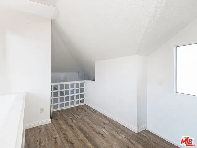 a view of an empty room with wooden floor and cabinet