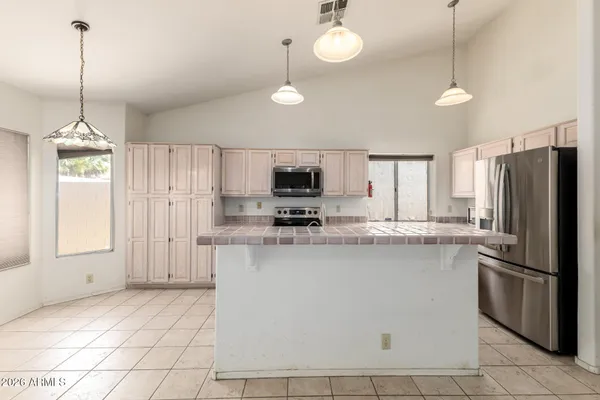 a kitchen with stainless steel appliances granite countertop a refrigerator a sink dishwasher a stove and white cabinets with wooden floor