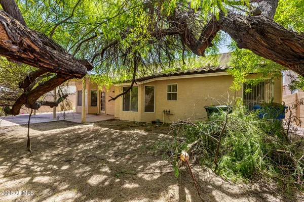 a backyard of a house with table and chairs under an umbrella