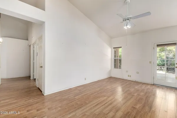 an empty room with wooden floor fan and windows