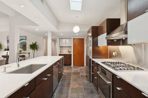 a kitchen with stainless steel appliances kitchen island granite countertop a sink stove and refrigerator