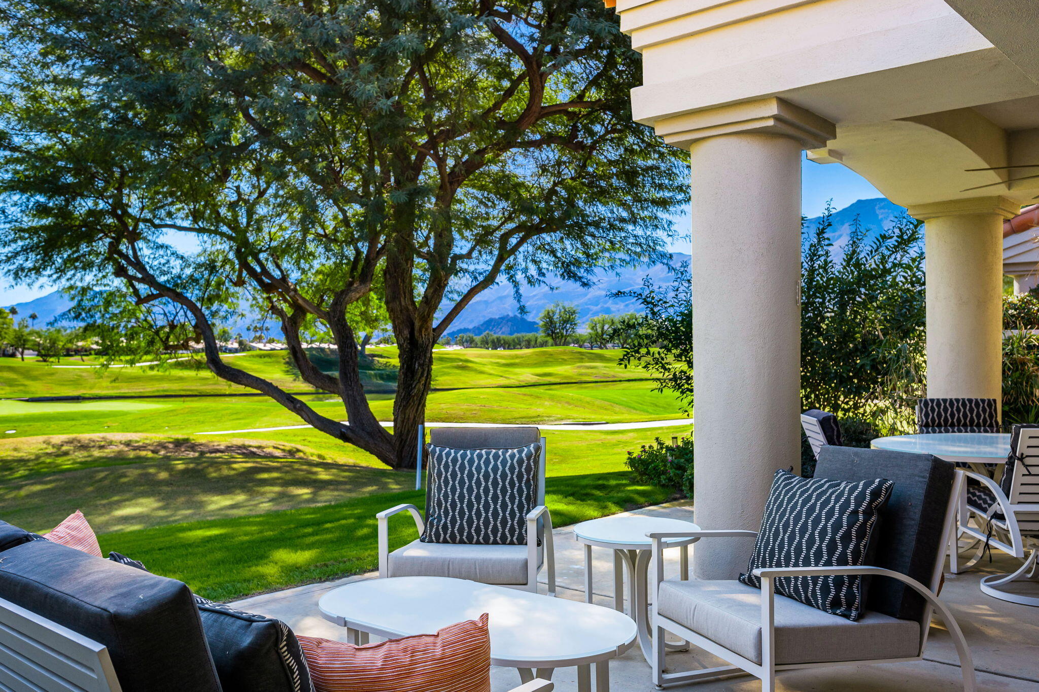 a view of a chairs and table in the patio next to a yard