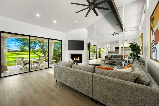 a living room with furniture floor to ceiling window and a flat screen tv