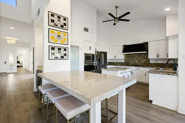 a living room with stainless steel appliances kitchen island a table chairs and a refrigerator